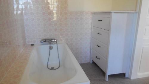 a bathroom with a bath tub next to a dresser at Guethary centre, Maison de Famille 10 couchages, classée 3 étoiles in Guéthary