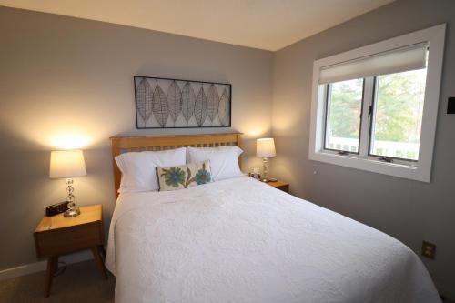 een slaapkamer met een wit bed en 2 ramen bij Beautiful Beach Front Condo With Lake Views in Bayfield