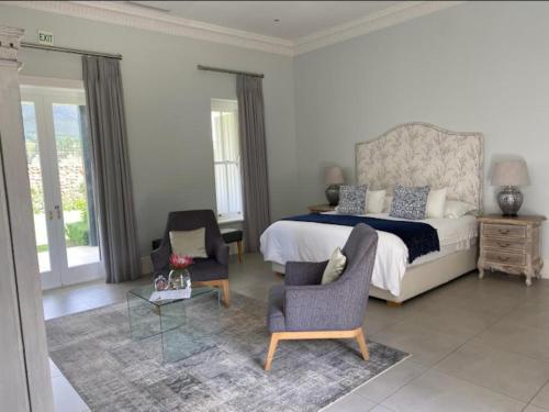 a bedroom with a bed and two chairs and a table at Chambray Estate - The Terraces in the Vines in Franschhoek