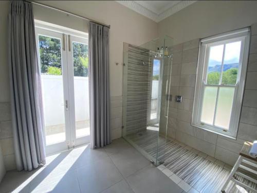 a bathroom with a walk in shower next to windows at Chambray Estate - The Terraces in the Vines in Franschhoek