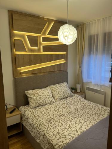 1 dormitorio con cama y lámpara de araña en Apartman MM Zlatibor en Zlatibor