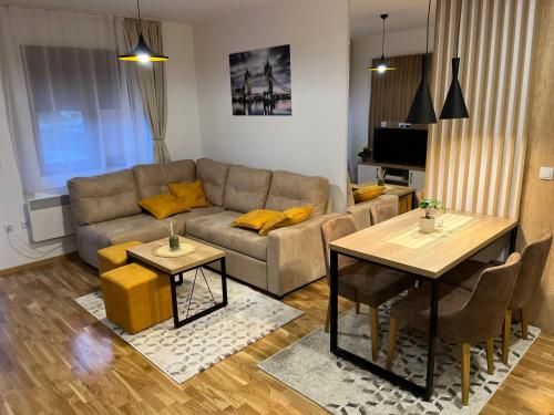 Apartman MM Zlatibor في زلاتيبور: غرفة معيشة مع أريكة وطاولة