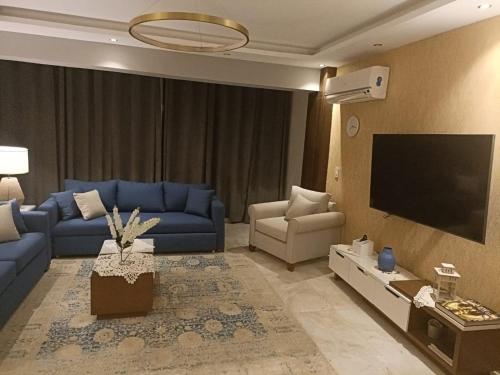 a living room with blue couches and a flat screen tv at حان الوقت الأن للاستمتاع بالهدوءبشقةفندقية متميزة بأطلالة على نيل الزمالك in Cairo