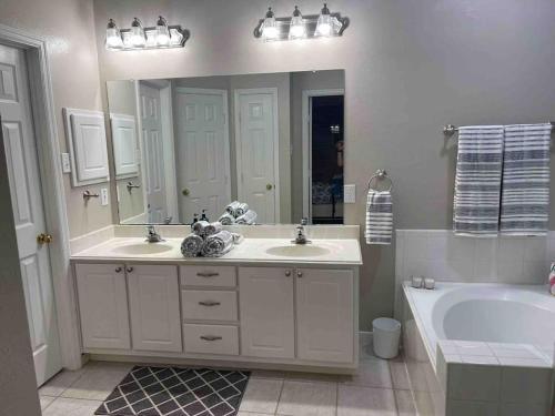 a bathroom with two sinks and a tub and a large mirror at Lovely Woodlands home w/heated pool and spa! in Spring