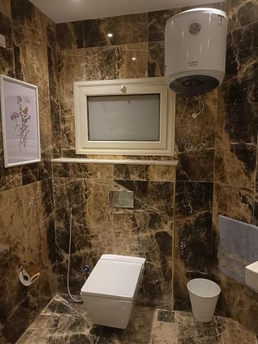 a bathroom with a toilet and a tv on the wall at حان الوقت الأن للاستمتاع بالهدوءبشقةفندقية متميزة بأطلالة على نيل الزمالك in Cairo