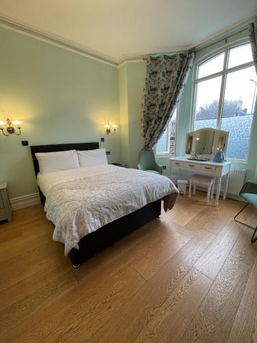 a bedroom with a bed and a desk and a window at Shandon Bells Guest House in Cork