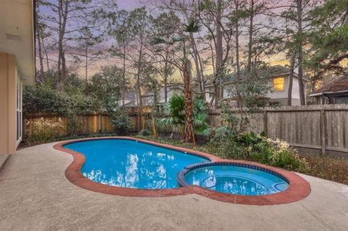 a swimming pool in a yard with a fence at Lovely Woodlands home w/heated pool and spa! in Spring