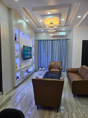 uma sala de estar com dois sofás e uma televisão em HEN - CAP SERVICED APARTMETS em Agege