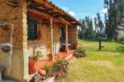 una casa de piedra con un porche con flores en un patio en CASITA CAMPESINA A 20 MIN DE SOGAMOSO, en Sogamoso