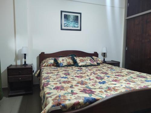 um quarto com uma cama com colcha floral em San Clemente frente al mar con cochera em San Clemente del Tuyú
