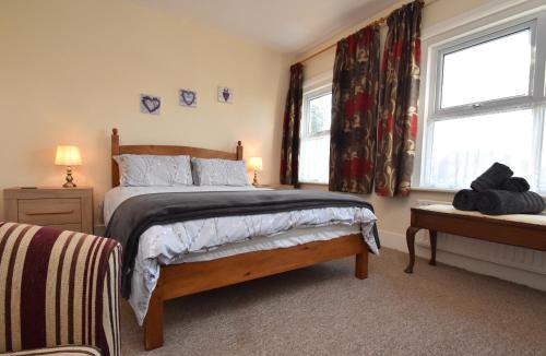 a bedroom with a bed and two windows at Tilling View with private parking in Rye