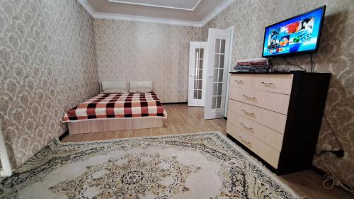 a bedroom with a bed and a dresser and a tv at Imanova 41 in Astana