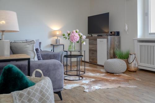 een woonkamer met een bank en een vaas met bloemen bij Ferienwohnung Königsmann in Strandnähe in Westerland