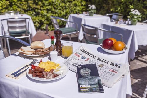a table with a plate of breakfast food and a newspaper at Grand Hotel Bonanno in Pisa