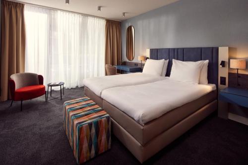 Cette chambre d'hôtel comprend un grand lit et un fauteuil rouge. dans l'établissement Van der Valk Hotel Hilversum/ De Witte Bergen, à Hilversum
