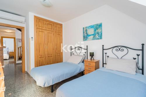 1 dormitorio con 2 camas y puerta de madera en Koti Rentals - Ático Gamycol en Fuengirola