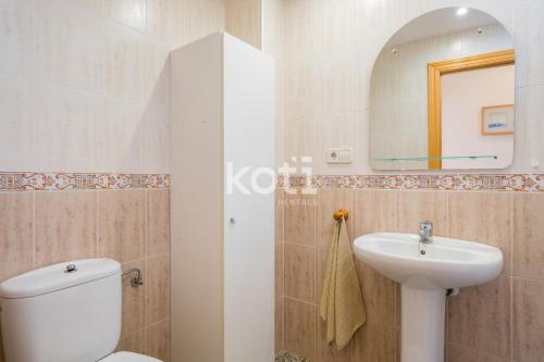 y baño con aseo blanco y lavamanos. en Koti Rentals - Ático Gamycol en Fuengirola