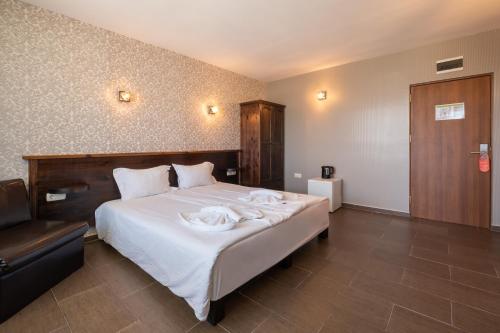 a bedroom with a bed with white sheets and a chair at Katalina SPA Resort in Tsigov Chark