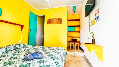 Proxima Estacion Hostel في ماسيو: غرفة نوم بسرير وجدار اصفر
