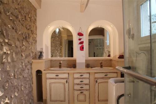 a bathroom with two sinks and two mirrors at Gîte de la font d'Arlane in Viviers