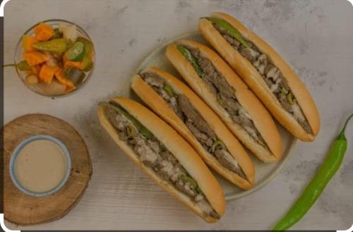 four hot dogs on a plate next to a bowl of vegetables at شقة مفروشة لك وحدك قريبة من مكتبة الاسكندرية in Alexandria