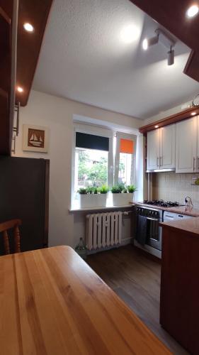 a kitchen with a wooden table and a window at Apartament Baltic Ustka in Ustka