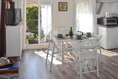 cocina con mesa y sillas blancas y TV en Les Agapanthes, en Vernon