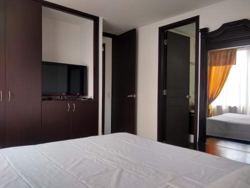 um quarto com uma cama e uma televisão de ecrã plano em APARTAMENTO VILLA OLÍMPICA em Pereira