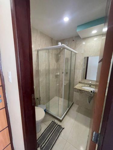 a bathroom with a shower and a toilet and a sink at Hotel Aconchego Da Vila in Saquarema