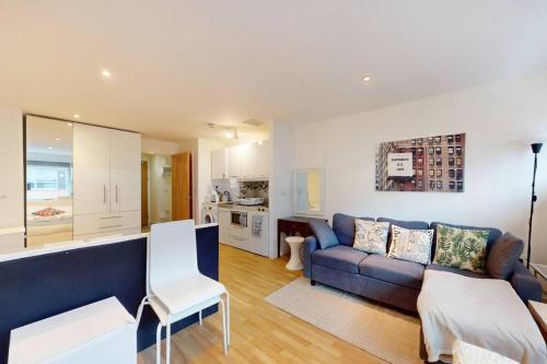 a living room with a blue couch and a kitchen at Stunning studio apt- 5 min walk to Borough station in London