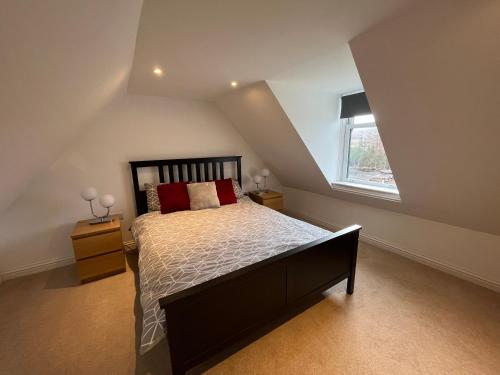 Schlafzimmer mit einem Bett mit roten Kissen und einem Fenster in der Unterkunft Alt-Na-Slat Cottage in Invergarry