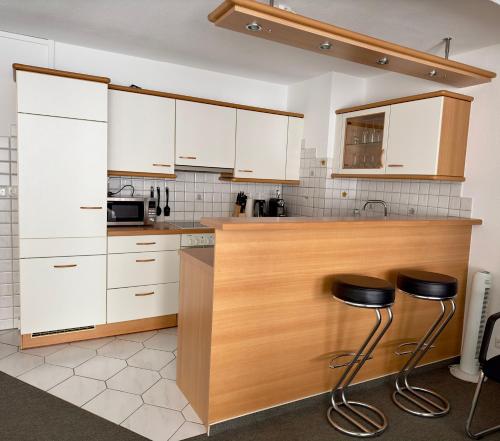 a kitchen with white cabinets and two stools at Ferienwohnung Sonitschka in Lörrach