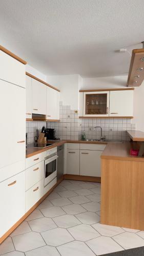 una cocina vacía con armarios blancos y una encimera en Ferienwohnung Sonitschka en Lörrach