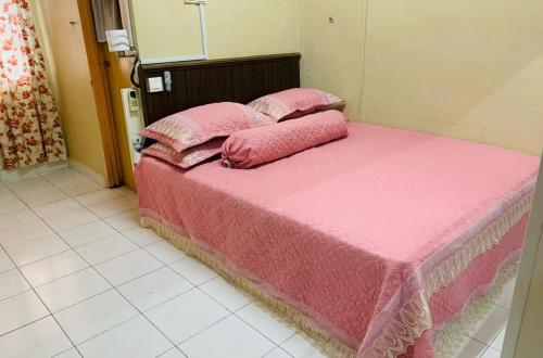 uma cama cor-de-rosa com lençóis e almofadas cor-de-rosa em zam homestay kulim perdana hitech utk Msliim shj em Kulim