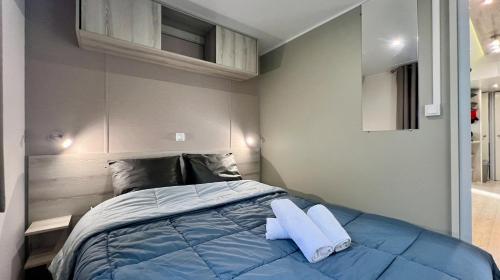 een slaapkamer met een blauw bed met 2 kussens bij Mobile-Home Le Mimosa Camping SIBLU**** in Fréjus