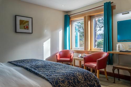 a bedroom with a bed and two chairs and a desk at Crubenbeg Country House in Newtonmore