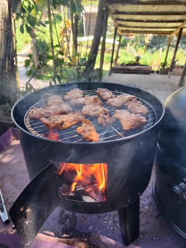 a grill with meat cooking on top of it at Residencial El Cielo Cabaña Popeye y Cabaña Pipil in Los Naranjos