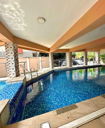 a large swimming pool with blue water in a building at Executive suite escape in Lekki