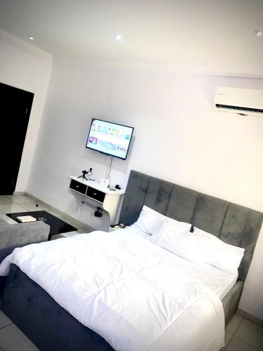 a bedroom with a white bed and a flat screen tv at Executive suite escape in Lekki