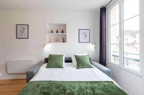 a white bedroom with a large bed with green pillows at Cœur de Fontainebleau: Confort, Calme & Haut débit in Fontainebleau