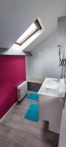 La salle de bains est pourvue d'un lavabo et d'un mur rouge. dans l'établissement Agréable maison de ville proche centre ville, à Nantes