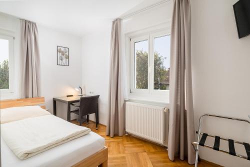 a bedroom with a bed and a desk and windows at WG-Haus in Landshut