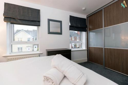 a bedroom with a white bed and two windows at Wharf House TSAC in Stockton-on-Tees