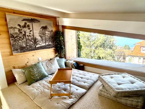 un salon avec un canapé et une grande fenêtre dans l'établissement Maison du garde barrière - Atypique et chaleureuse, à Évian-les-Bains