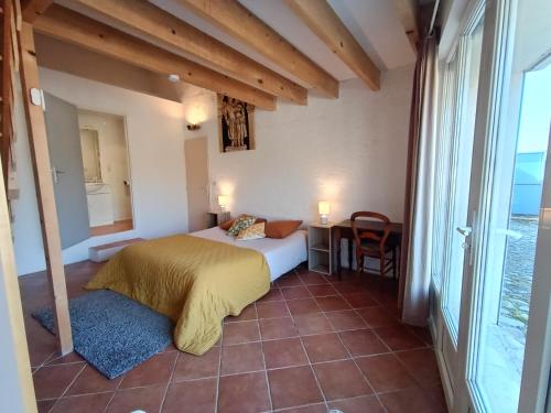 1 dormitorio con cama, mesa y ventana en Maison de village, en Mollans-sur-Ouvèze