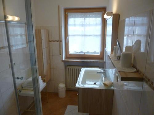 uma casa de banho com um lavatório, um chuveiro e um WC. em Ferienwohnung Edmeier em Bernau am Chiemsee