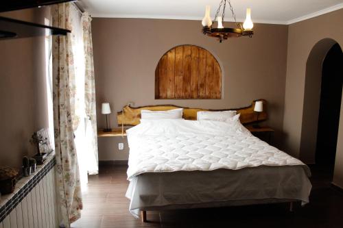 a bedroom with a white bed with a wooden headboard at Pensiunea Taverna Bucium in Iaşi