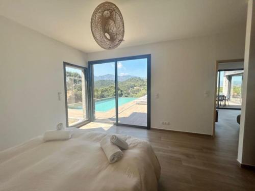 - une chambre blanche avec un grand lit et une grande fenêtre dans l'établissement Villa Trinita Paradis privé piscine et loisirs, à Porto-Vecchio