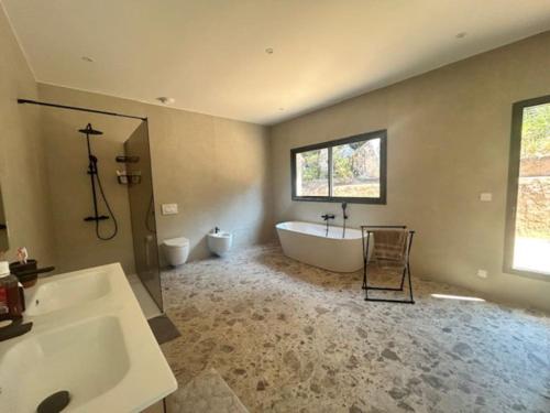La grande salle de bains est pourvue d'une grande baignoire et d'un lavabo. dans l'établissement Villa Trinita Paradis privé piscine et loisirs, à Porto-Vecchio