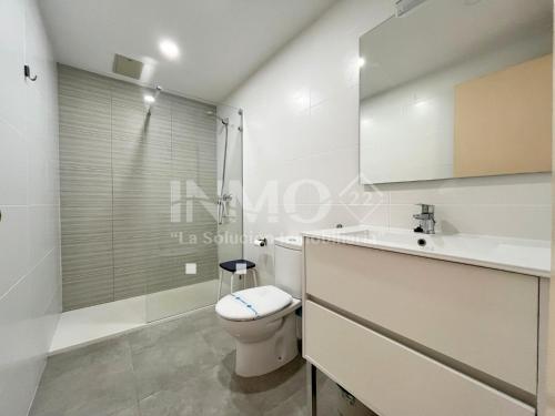 a white bathroom with a toilet and a sink at Apartamento frente al mar en La Llosa Edif Olimpic 103A - INMO22 in Cambrils